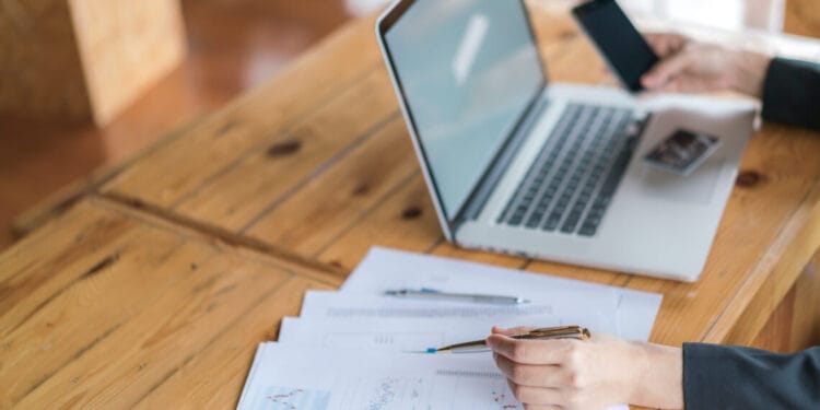 Business woman hand with Financial charts and laptop on the table