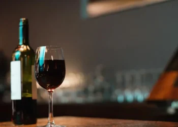 Copo de vinho tinto e garrafa no balcão do bar • Freepick/wavebreakmedia_micro