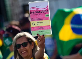 Mulher em manifestação pró-Bolsonaro segura cartaz com desenho de caixa de ivermectina crédito: Getty Images