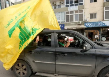 Um homem gesticula enquanto segura bandeira do Hezbollah no segundo dia do cessar-fogo entre Israel e o grupo apoiado pelo Irã em Tiro, no sul do Líbano28/11/2024REUTERS/Aziz Taher • REUTERS